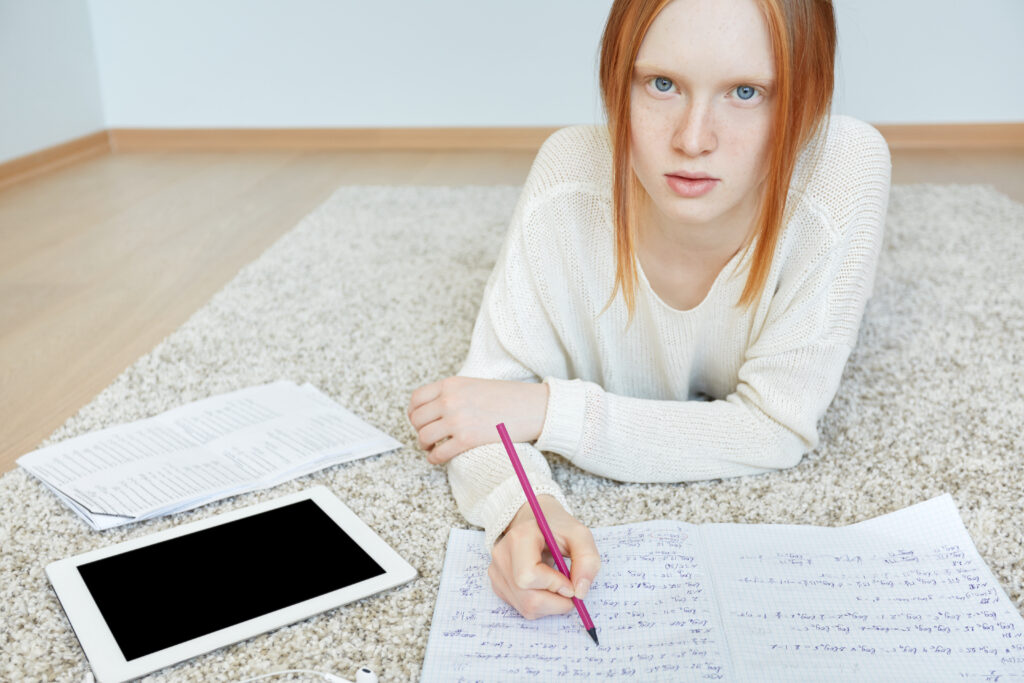 redhead woman lying floor with notebook tablet