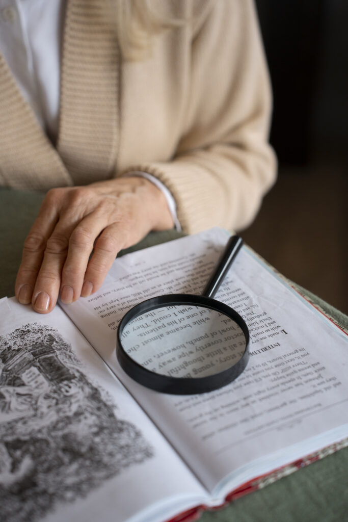 elderly woman reading while using magnifying glass